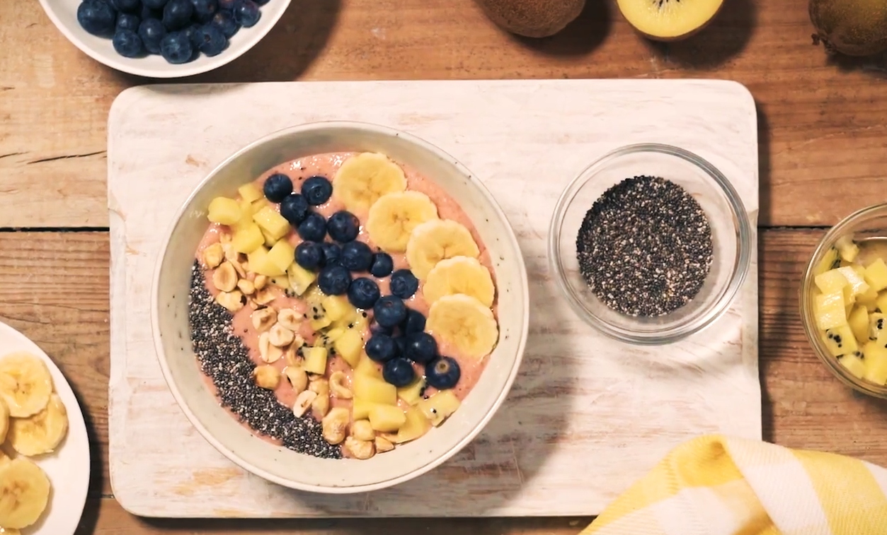 Frühstücksbowl mit gelber Kiwi, roten Früchten und Chiasamen